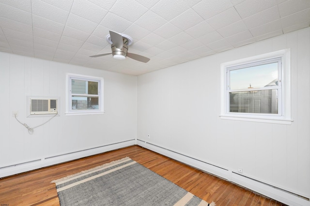 unfurnished room featuring wood-type flooring, a wealth of natural light, and baseboard heating