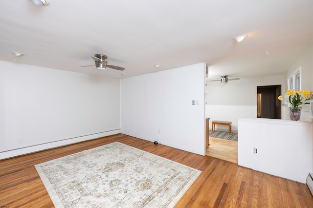 unfurnished room with a baseboard heating unit, hardwood / wood-style flooring, and ceiling fan