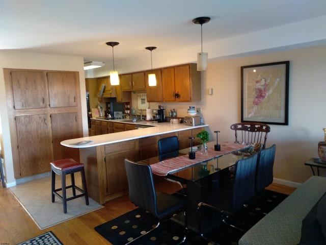 kitchen featuring kitchen peninsula, a breakfast bar area, light hardwood / wood-style flooring, sink, and decorative light fixtures