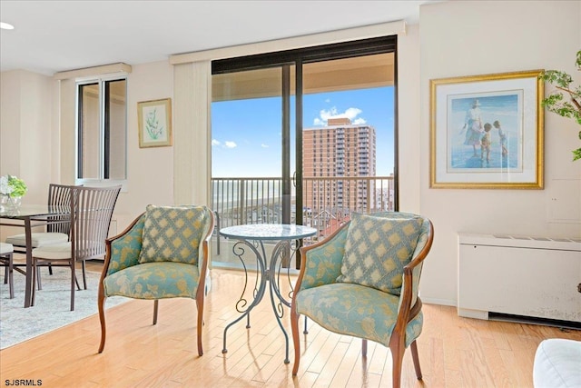 sitting room featuring expansive windows, light hardwood / wood-style flooring, and radiator heating unit