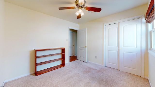 unfurnished bedroom featuring light carpet, a closet, and ceiling fan