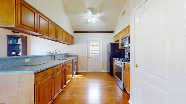 kitchen featuring sink, light hardwood / wood-style flooring, stainless steel appliances, and vaulted ceiling