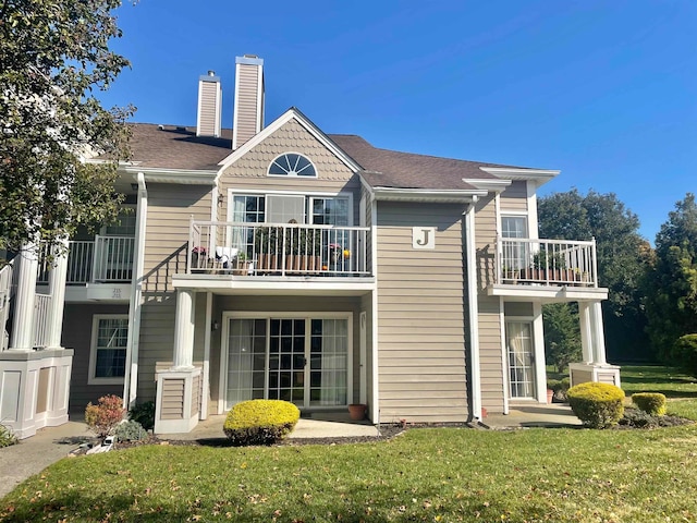 back of house featuring a balcony and a yard