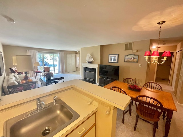 kitchen featuring light carpet, kitchen peninsula, sink, and hanging light fixtures