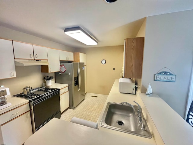 kitchen with stainless steel refrigerator with ice dispenser, black range, and sink