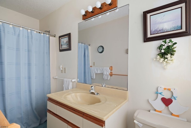 bathroom with vanity, toilet, a textured ceiling, and walk in shower