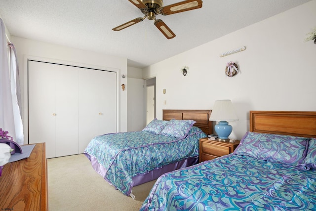 bedroom with a closet, a textured ceiling, light colored carpet, and ceiling fan