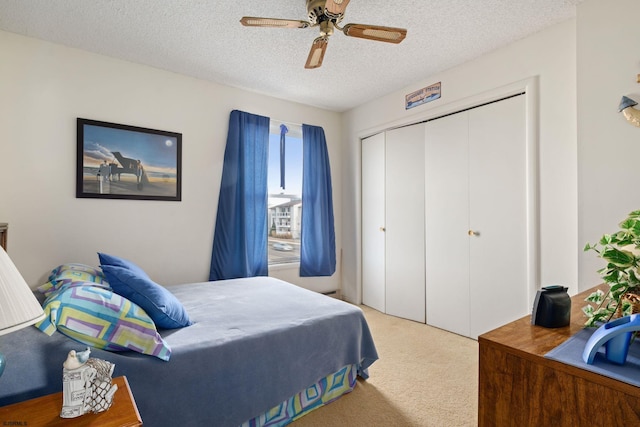 carpeted bedroom with a closet, ceiling fan, and a textured ceiling