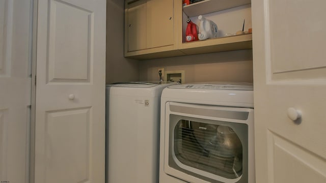 laundry room with washing machine and dryer and cabinets