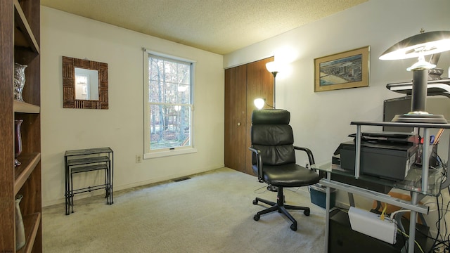 carpeted home office featuring a textured ceiling