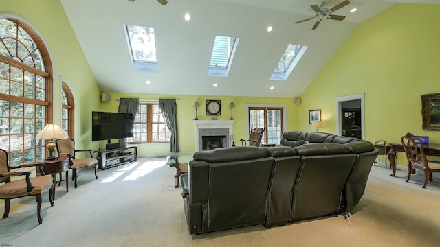 living room featuring a healthy amount of sunlight, high vaulted ceiling, a skylight, and ceiling fan