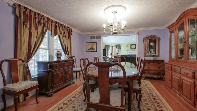 dining room with ornamental molding, a chandelier, light wood-type flooring, and a textured ceiling