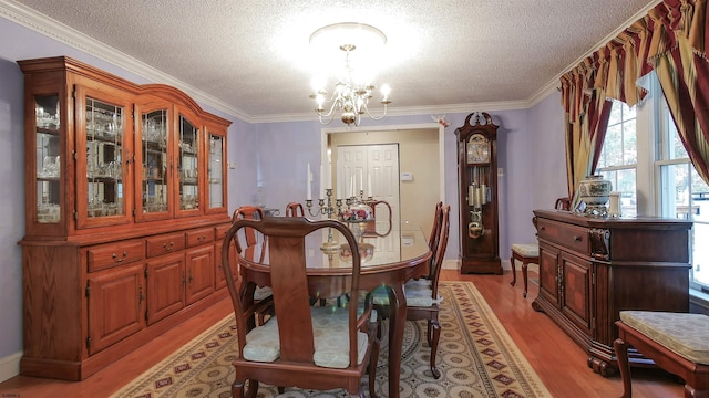 dining room with light hardwood / wood-style floors, a notable chandelier, ornamental molding, and a textured ceiling