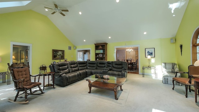 carpeted living room featuring high vaulted ceiling, a skylight, and ceiling fan with notable chandelier