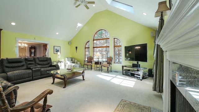 carpeted living room with high vaulted ceiling, ceiling fan with notable chandelier, and a skylight