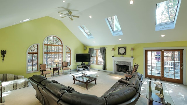 living room featuring ceiling fan, light colored carpet, high vaulted ceiling, and a skylight