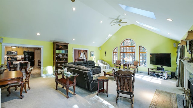 living room featuring lofted ceiling with skylight, light carpet, and ceiling fan