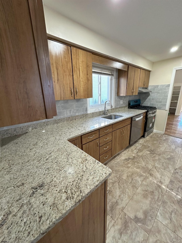 kitchen with appliances with stainless steel finishes, tasteful backsplash, sink, and light stone counters