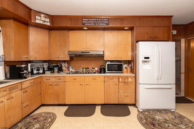 kitchen featuring black electric stovetop and white refrigerator with ice dispenser