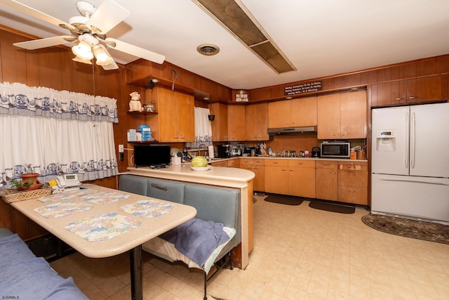 kitchen with kitchen peninsula, stainless steel appliances, sink, ceiling fan, and wood walls