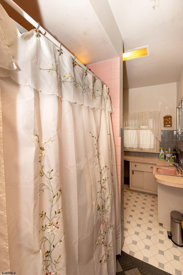 bathroom featuring tasteful backsplash, sink, and a shower with shower curtain