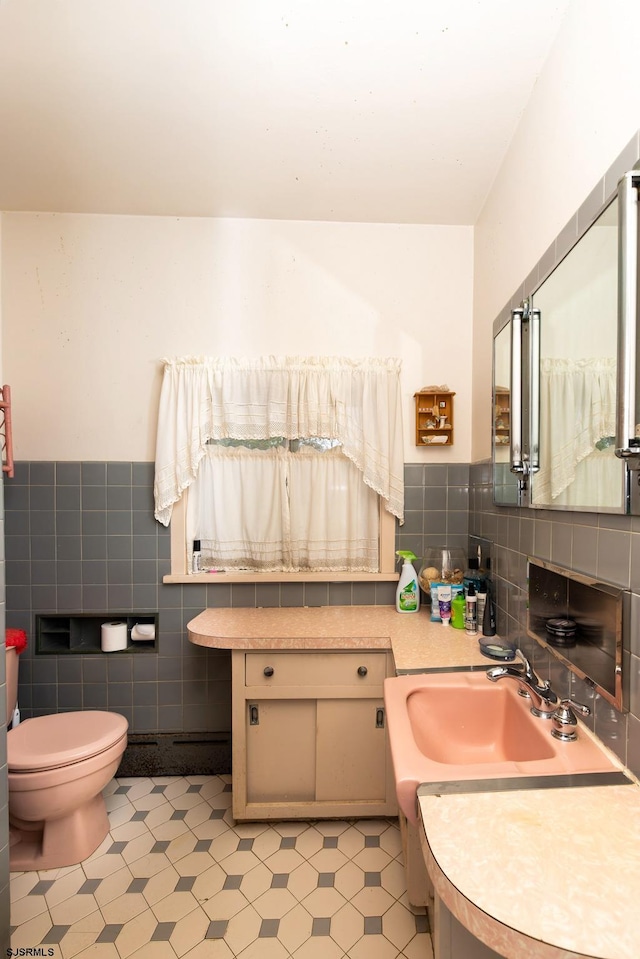 bathroom with vanity, tile walls, and toilet