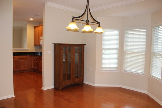 unfurnished dining area featuring crown molding, a notable chandelier, and dark wood-type flooring