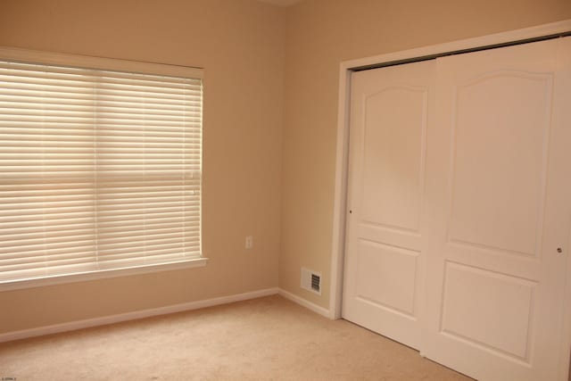 unfurnished bedroom featuring light colored carpet and a closet