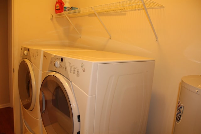 clothes washing area featuring water heater and washer and clothes dryer