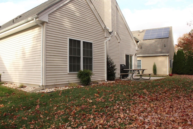 view of home's exterior with solar panels and a patio