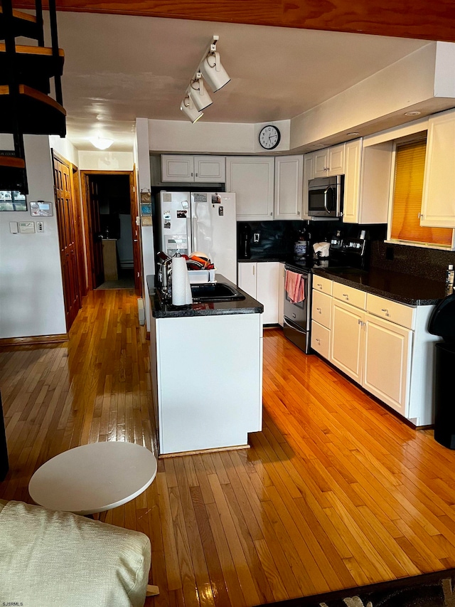 kitchen featuring white cabinetry, backsplash, stainless steel appliances, and light wood-type flooring