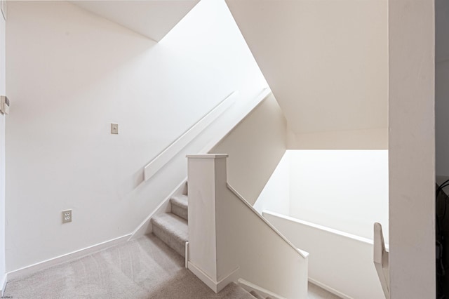 stairway with lofted ceiling and carpet flooring