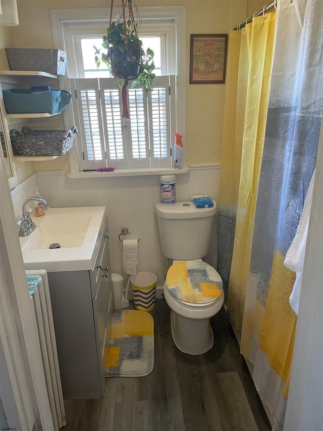 bathroom featuring radiator heating unit, wood-type flooring, vanity, curtained shower, and toilet