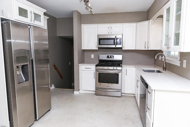 kitchen featuring stainless steel appliances, white cabinets, sink, and rail lighting