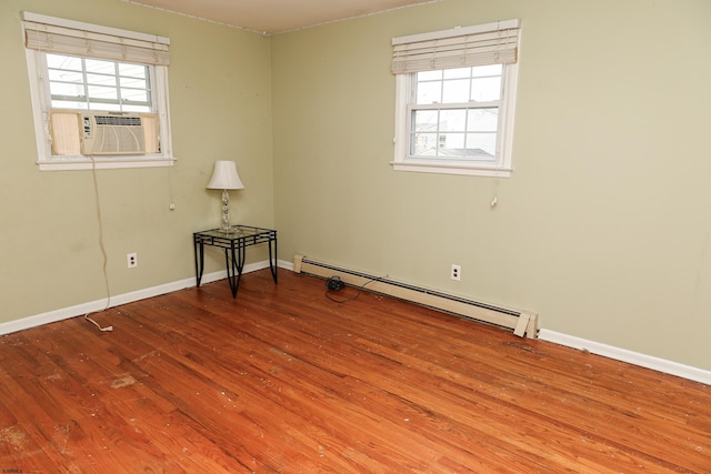 empty room featuring hardwood / wood-style floors, a healthy amount of sunlight, and a baseboard radiator