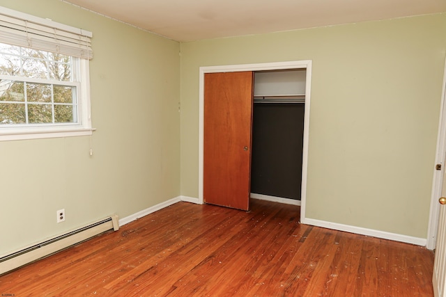 unfurnished bedroom featuring dark hardwood / wood-style floors, a baseboard radiator, and a closet