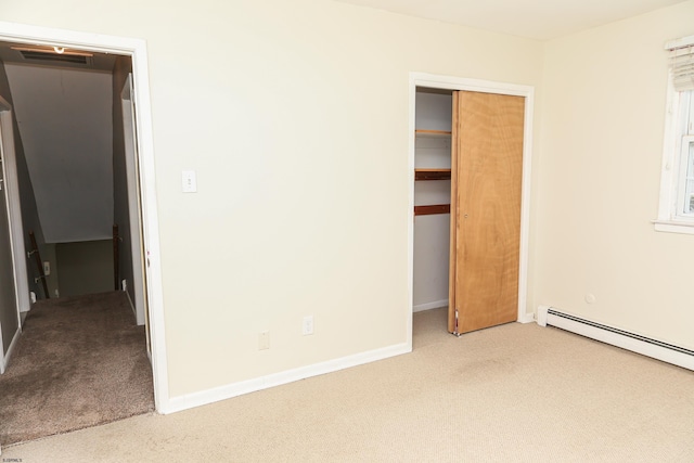 unfurnished bedroom with a closet, light colored carpet, and a baseboard heating unit