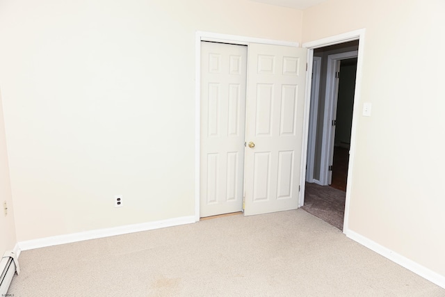 unfurnished bedroom featuring baseboard heating, a closet, and carpet