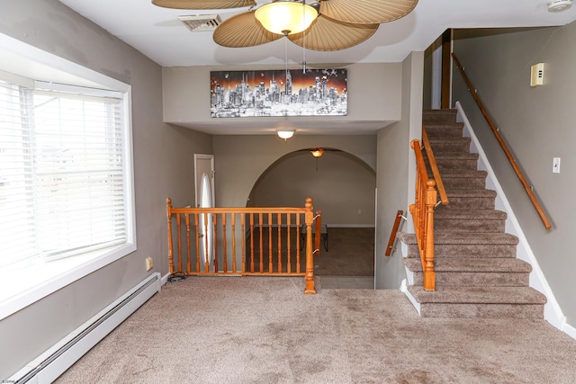 stairway with baseboard heating, carpet flooring, and ceiling fan