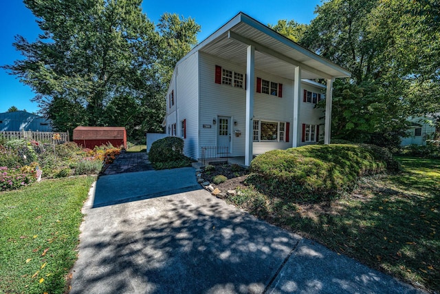 view of front of property featuring a front lawn, a shed, and covered porch