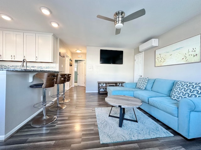 living room featuring dark hardwood / wood-style floors, ceiling fan, sink, and a wall mounted air conditioner