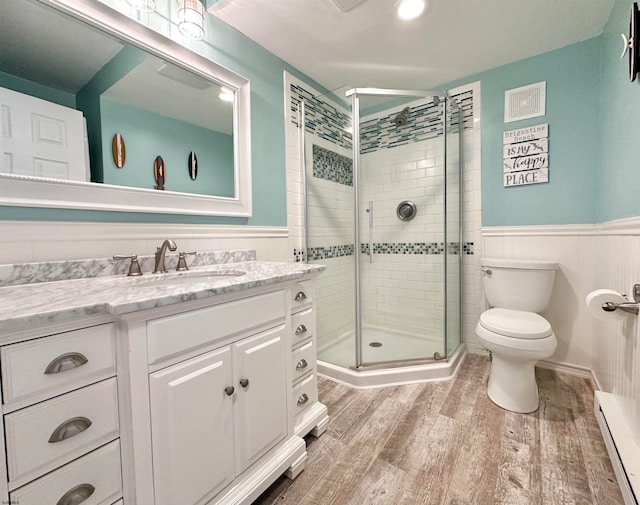 bathroom with a baseboard radiator, wood-type flooring, toilet, vanity, and a shower with shower door