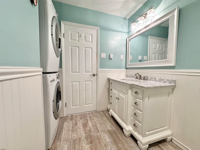 bathroom featuring stacked washing maching and dryer, vanity, and hardwood / wood-style flooring