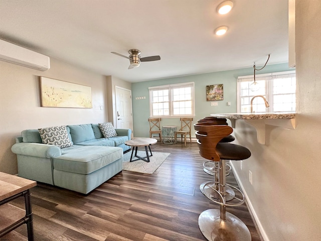 living room featuring dark wood-type flooring, ceiling fan, and a wall mounted AC