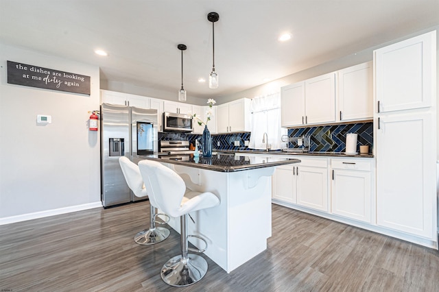 kitchen featuring a kitchen island, backsplash, appliances with stainless steel finishes, dark hardwood / wood-style flooring, and white cabinets