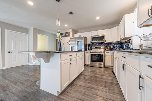 kitchen featuring white cabinetry, a breakfast bar, appliances with stainless steel finishes, dark hardwood / wood-style floors, and a kitchen island