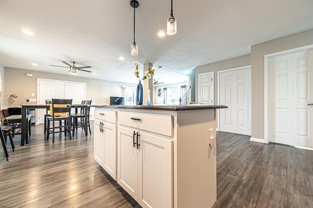 kitchen with white cabinets, hanging light fixtures, dark hardwood / wood-style floors, and a kitchen island