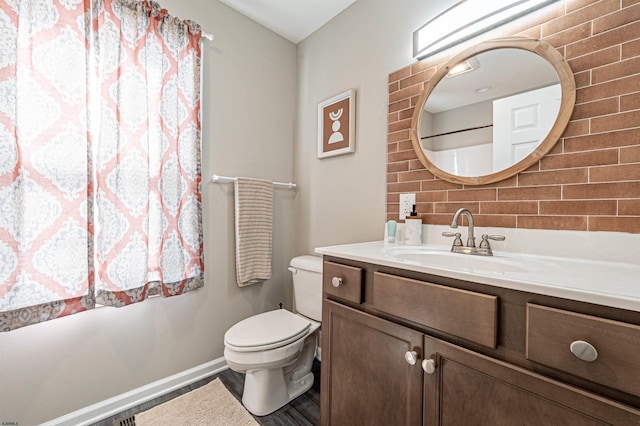 bathroom featuring vanity, toilet, and tasteful backsplash