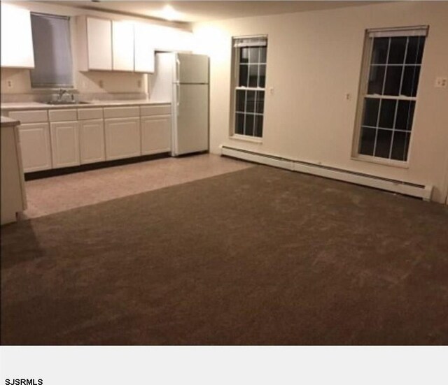 kitchen featuring white cabinetry, sink, baseboard heating, light colored carpet, and white refrigerator