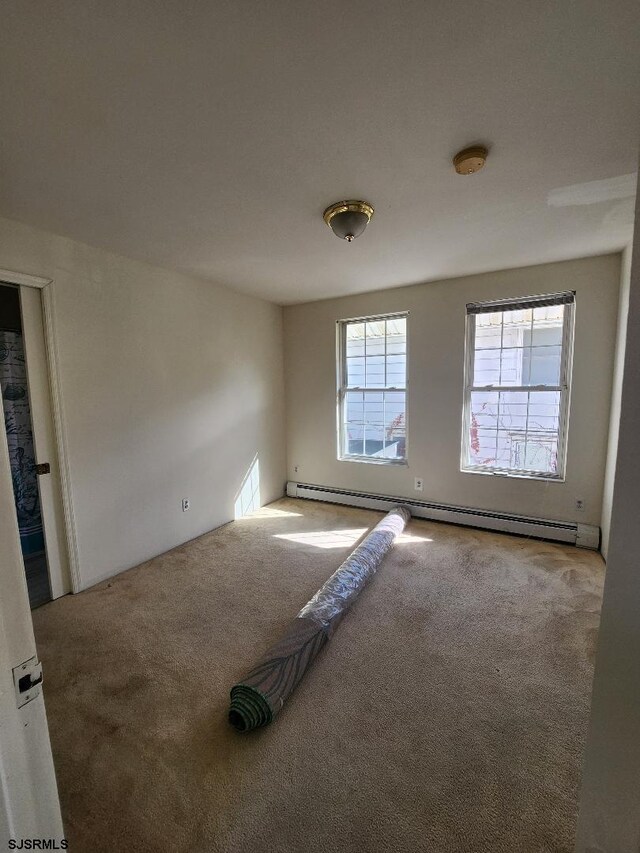 carpeted spare room featuring a baseboard heating unit